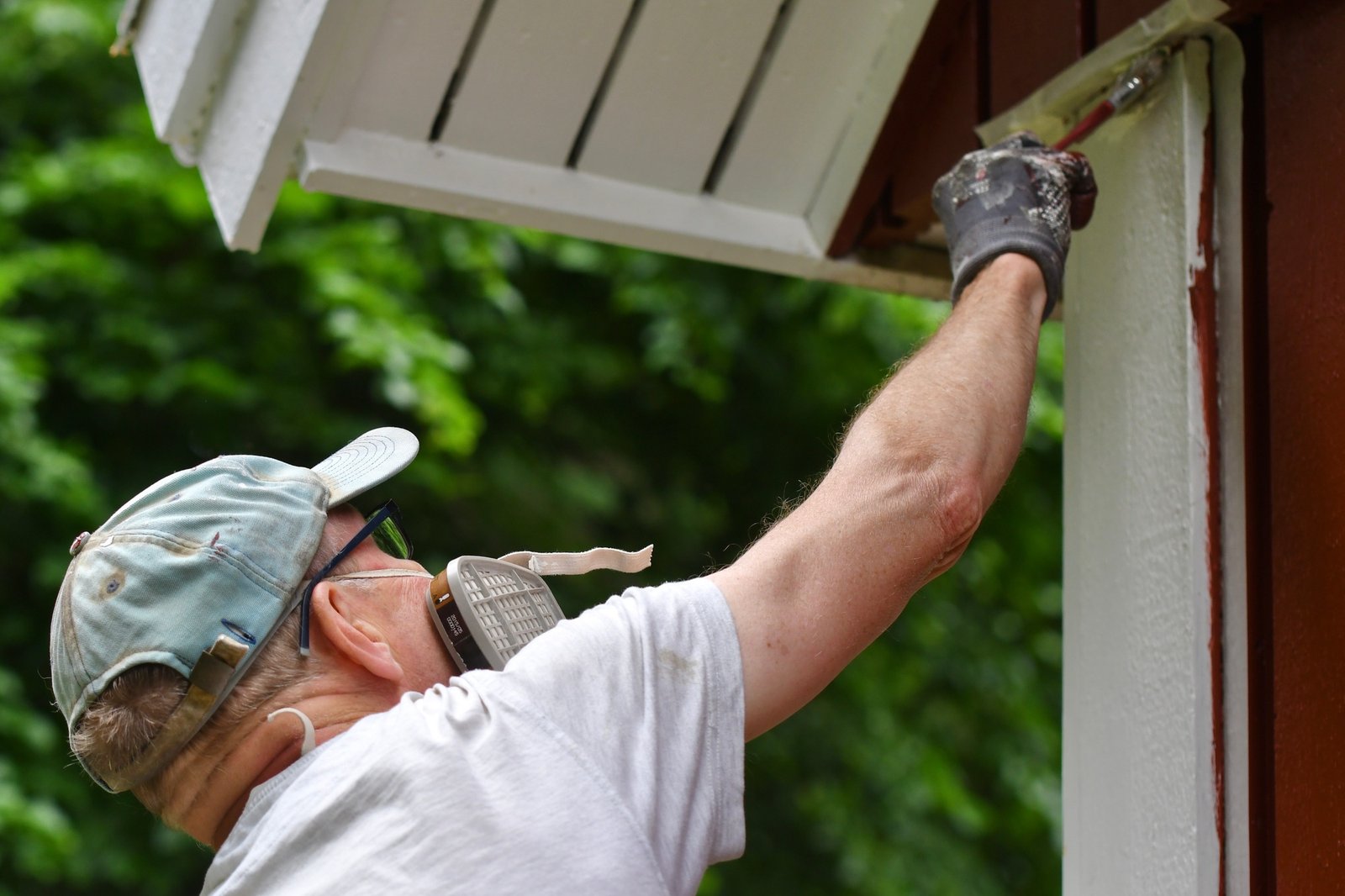 a man painting house exterior with white color