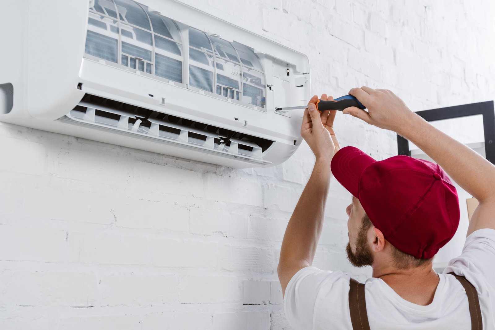 close up shot of professional repairman changing filter for air conditioner with screwdriver