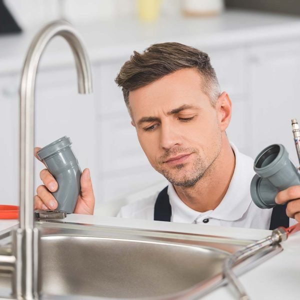 thoughtful adult repairman holding pipes and tools resize